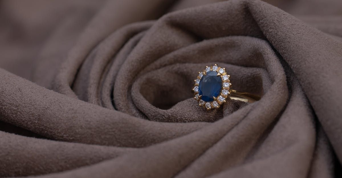 A gold ring with a sapphire and diamonds on a brown cloth