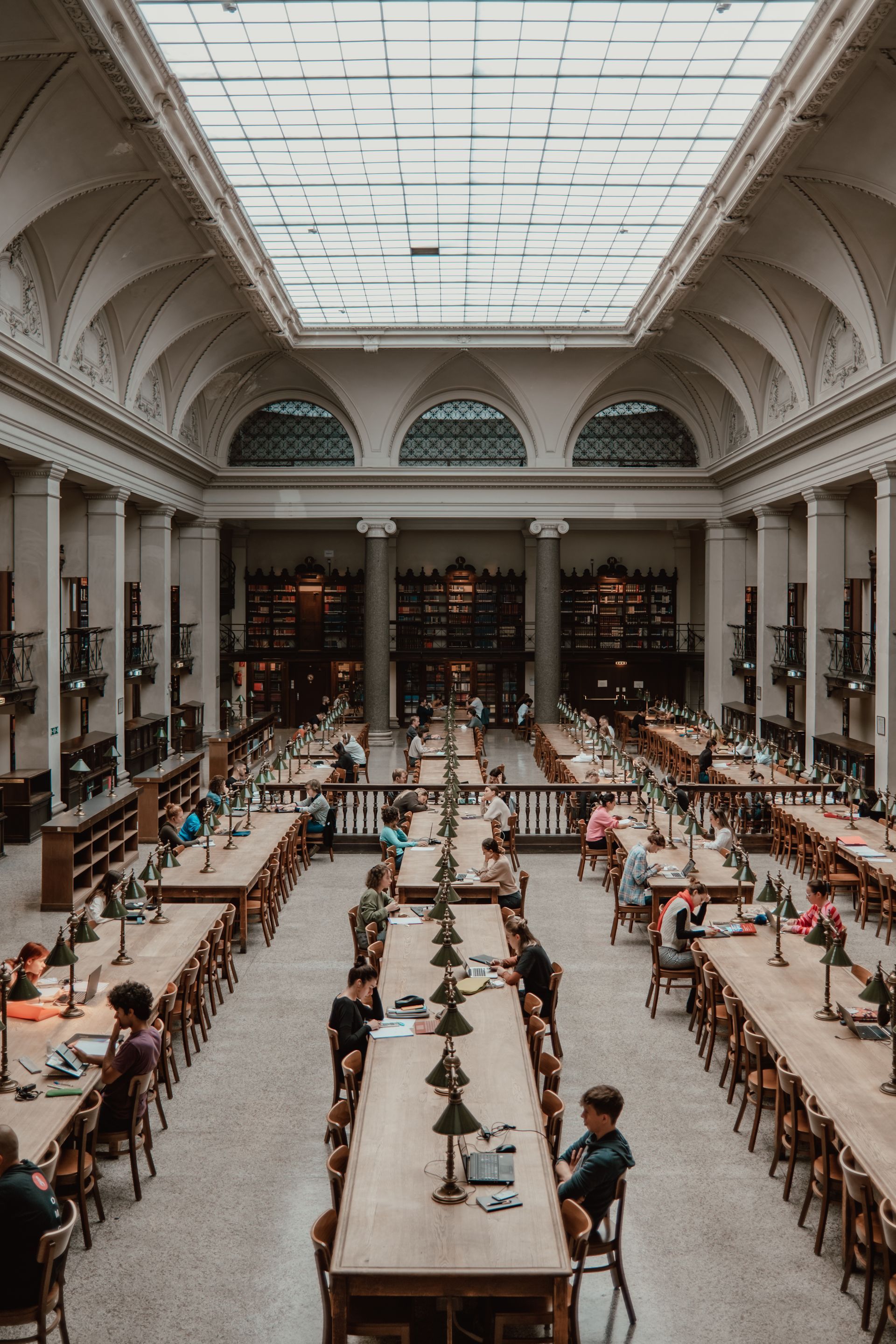 people are sitting at long tables in a library