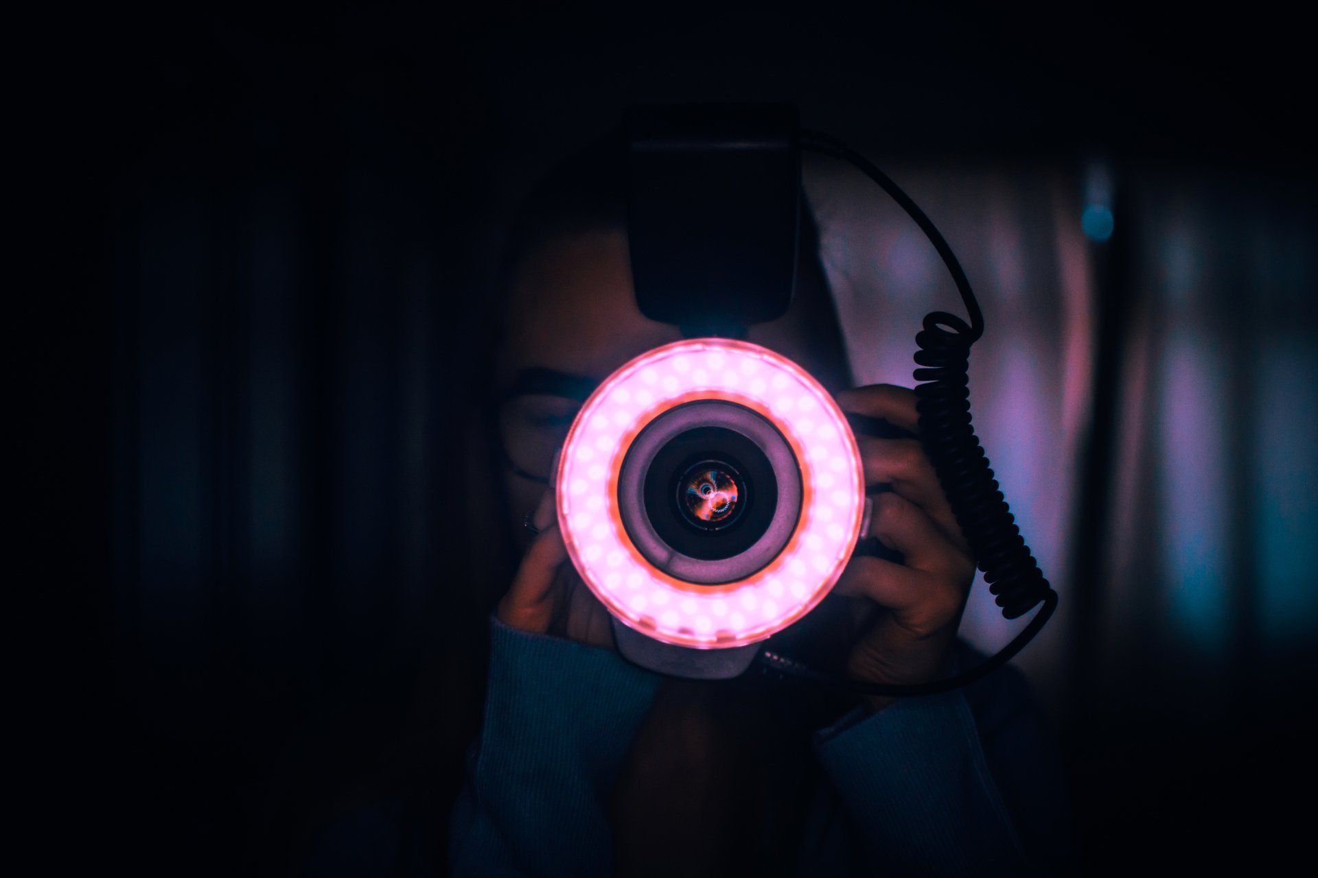 une personne tient un appareil photo avec une lumière rose autour de l' objectif