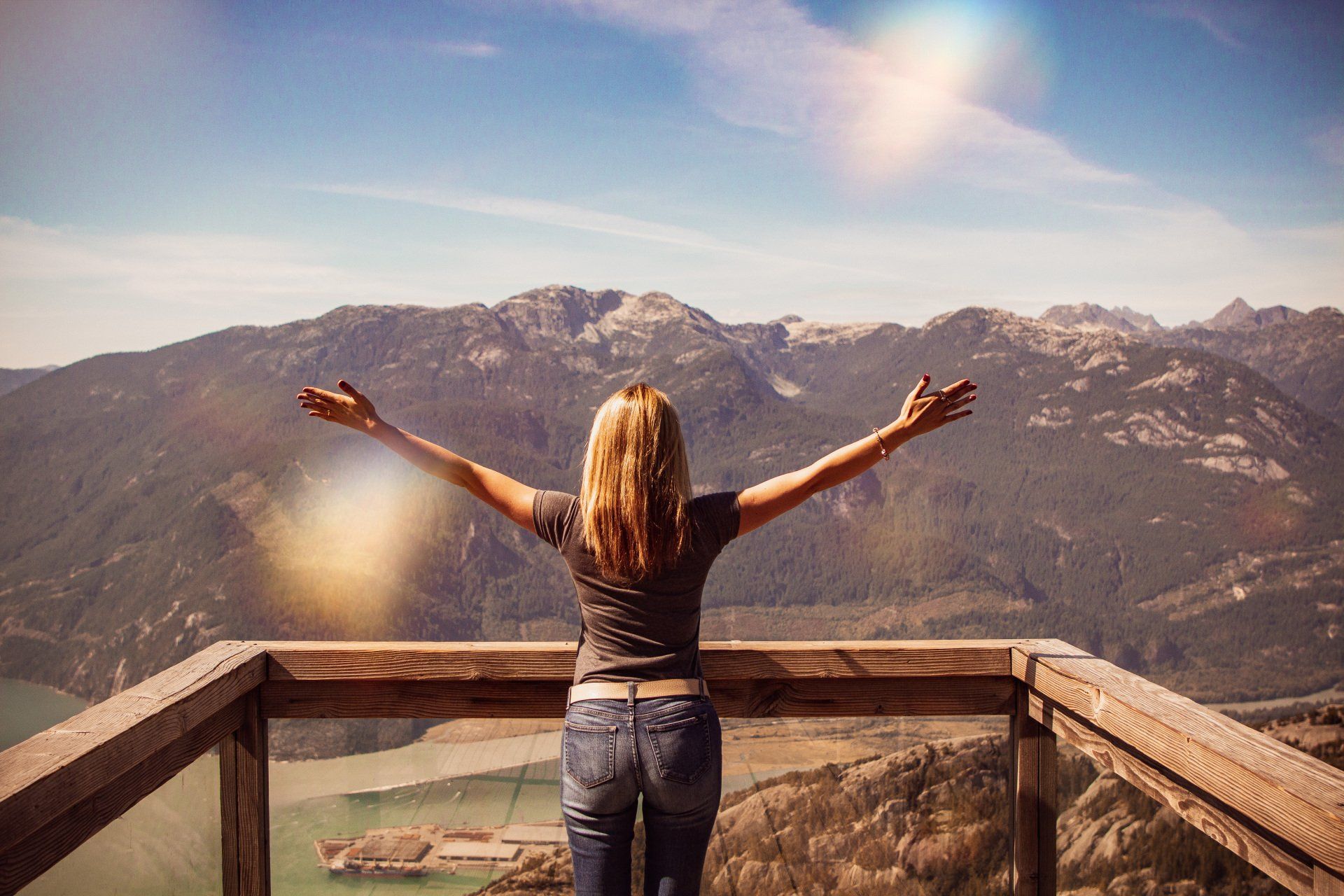 Woman looking at beautiful mountains, lifts her arms in surrender to God.