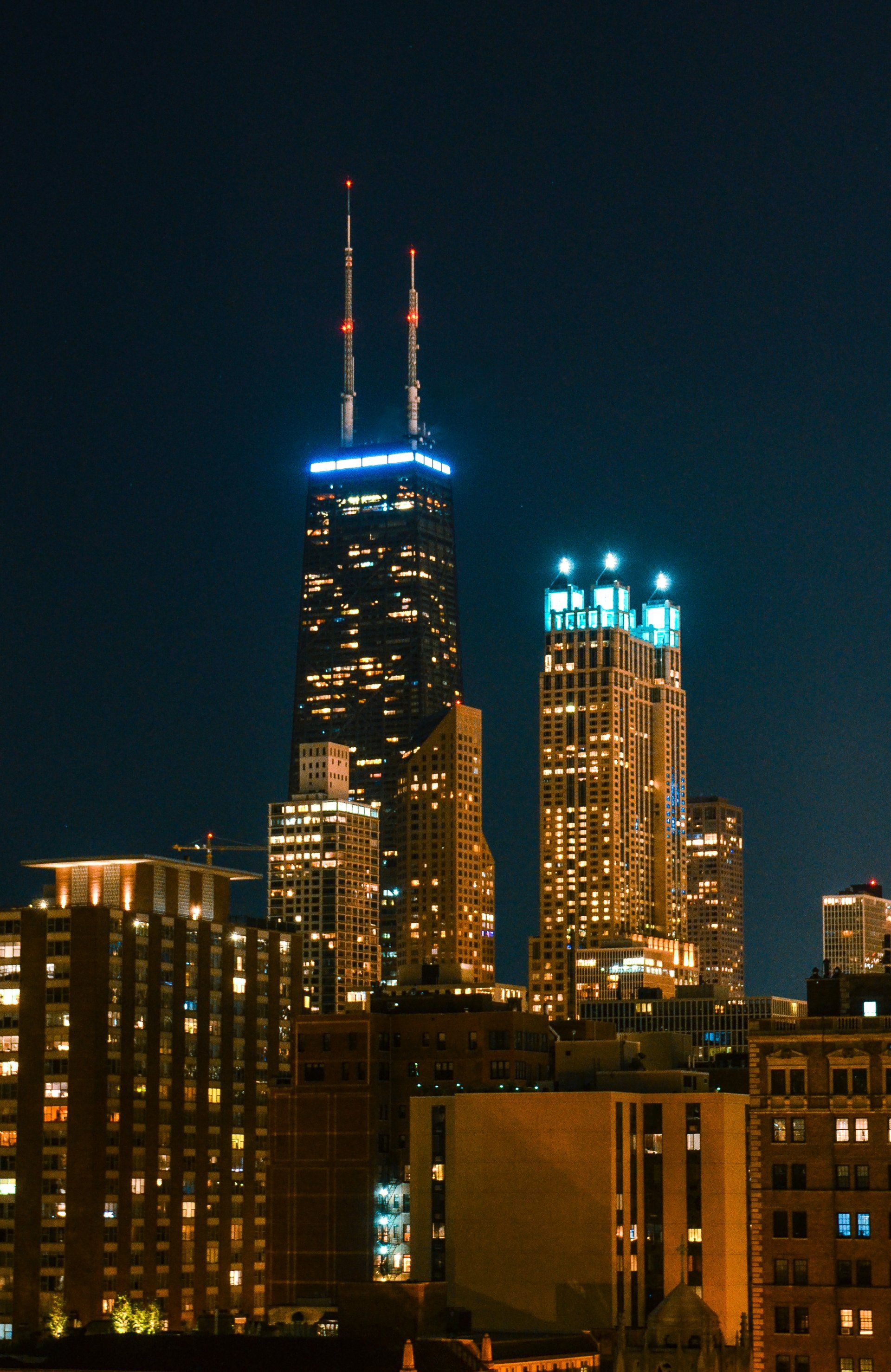 A city skyline at night with a few buildings lit up