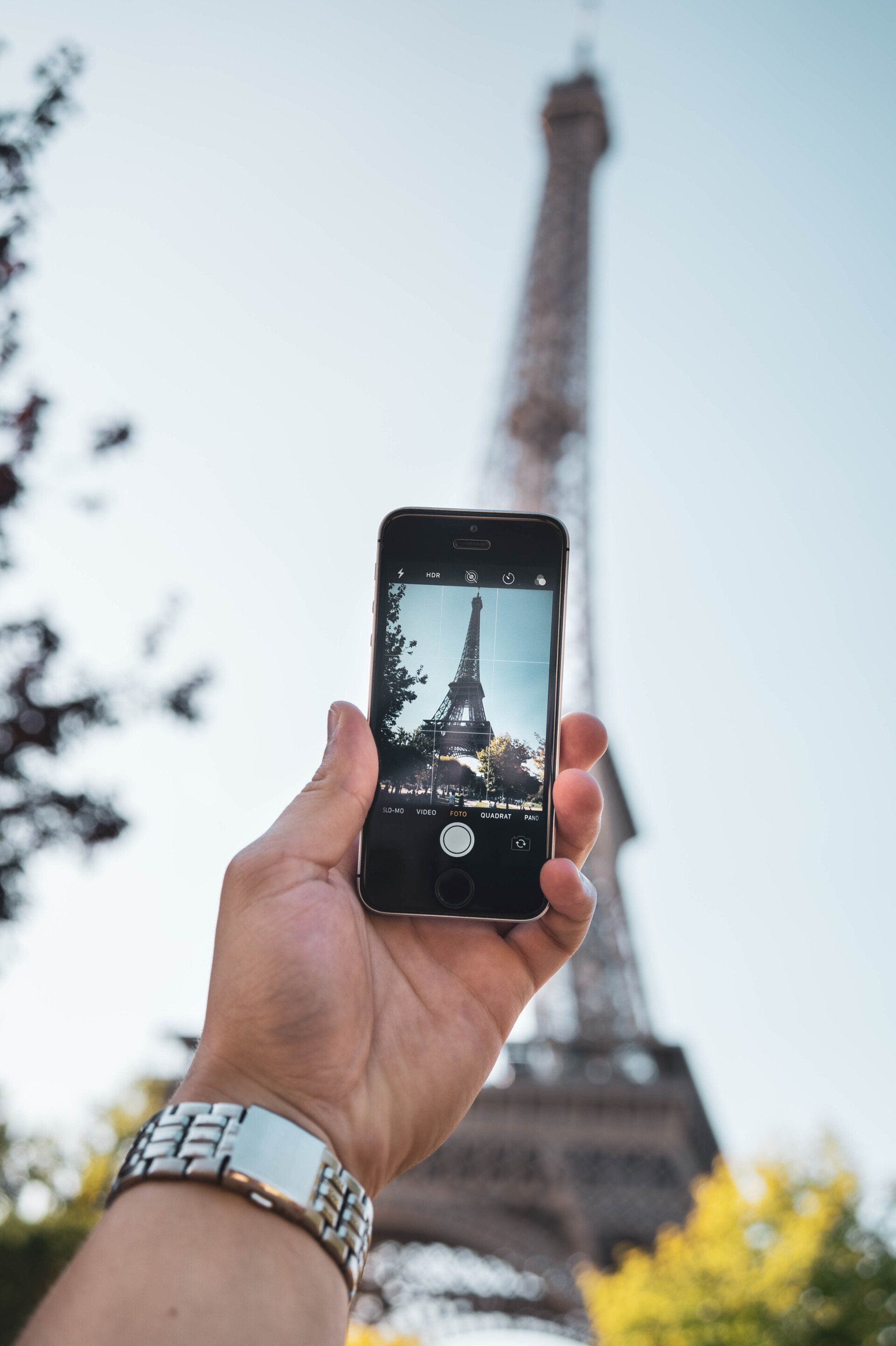 A person is taking a picture of the eiffel tower with a cell phone.