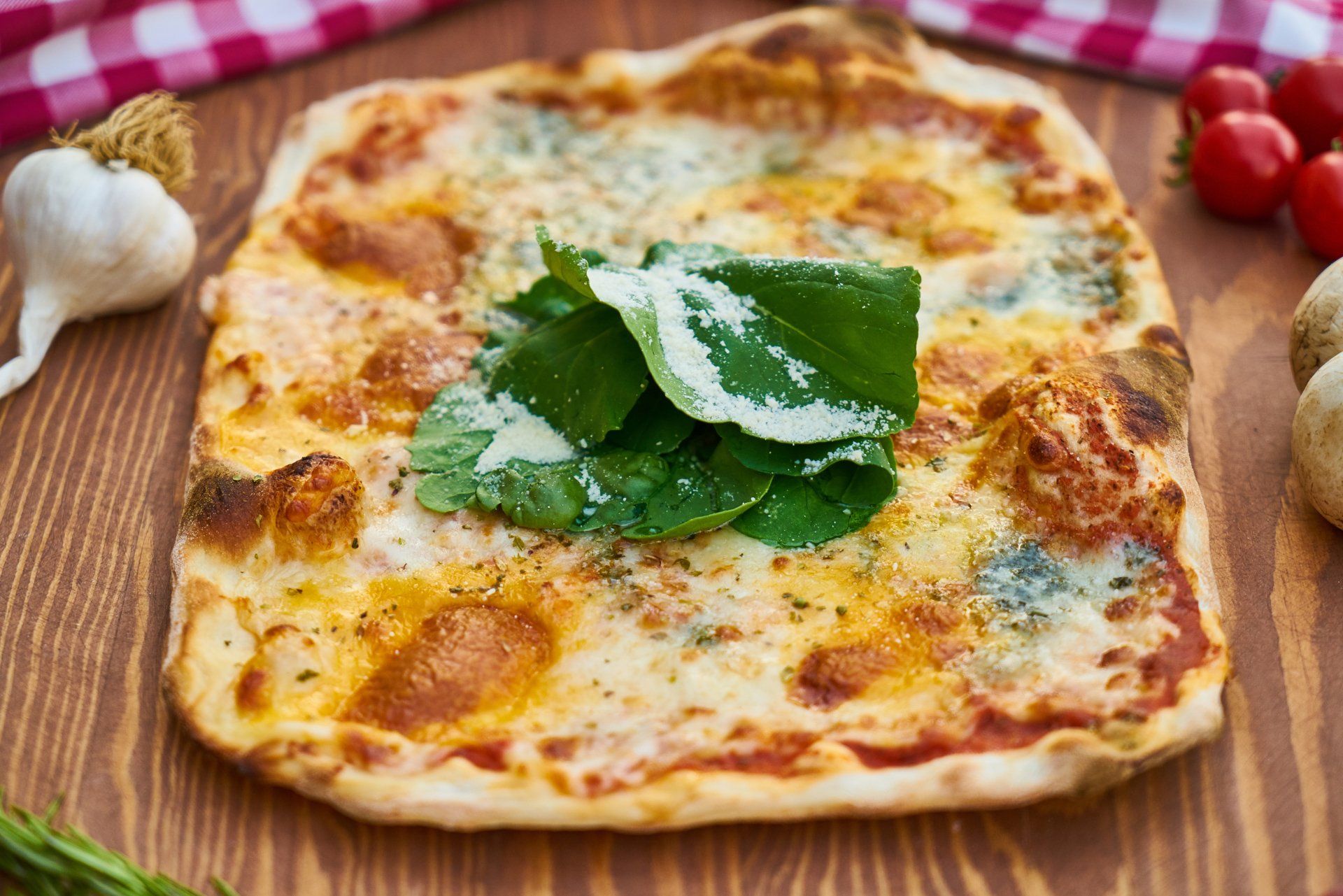 A pizza with spinach and cheese is sitting on a wooden table.