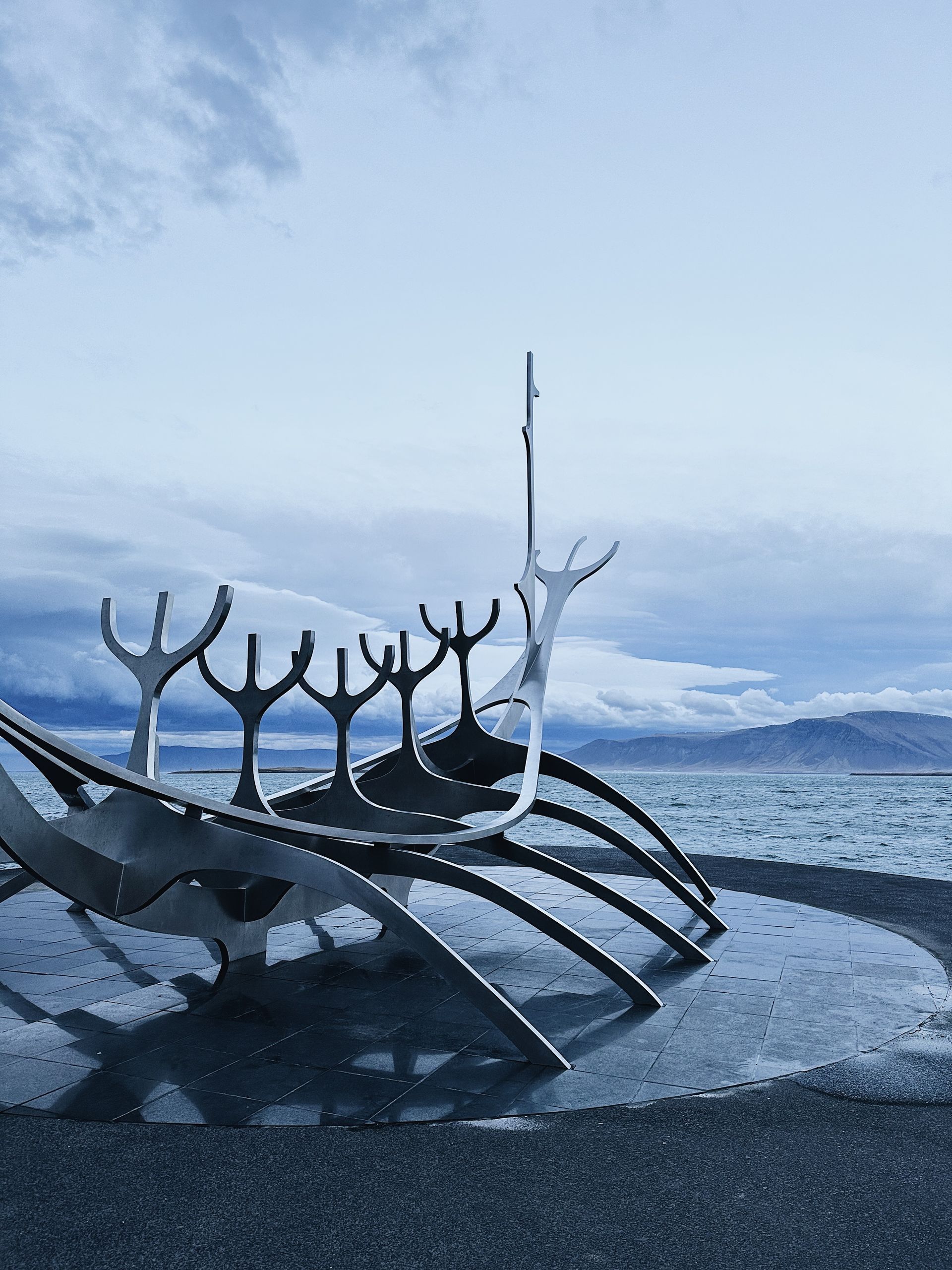 A sculpture of a boat is on the beach near the ocean