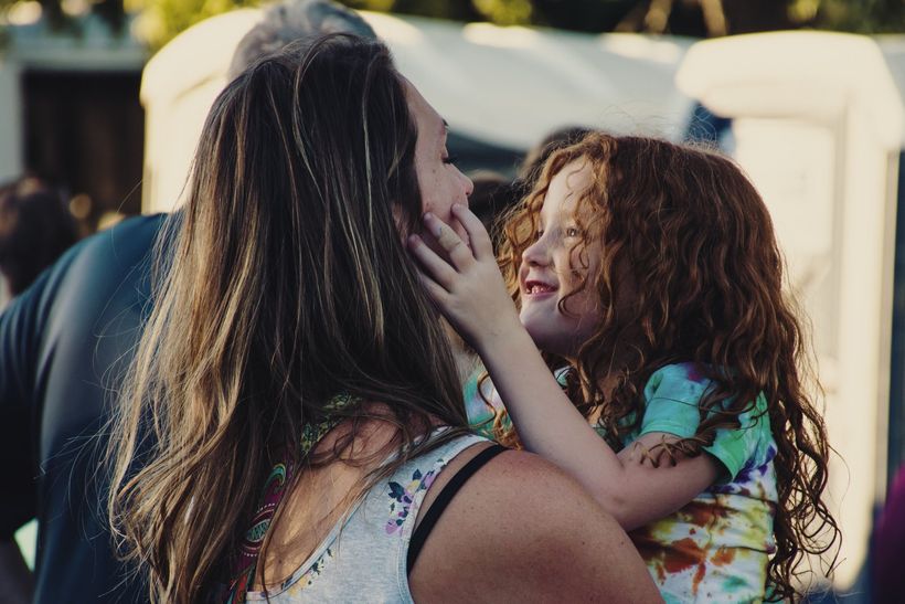 a woman is holding a little girl in her arms .