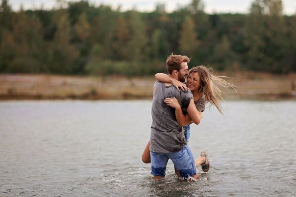 A man is holding a woman in his arms in the water.