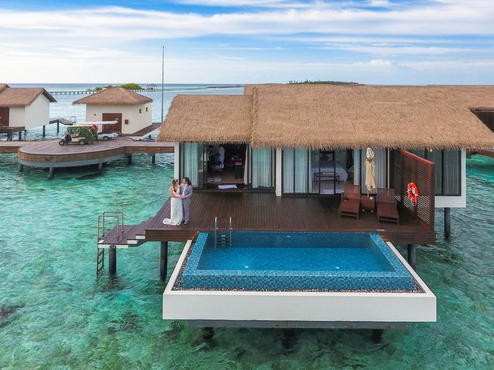 An aerial view of a house with a swimming pool in the middle of the ocean.