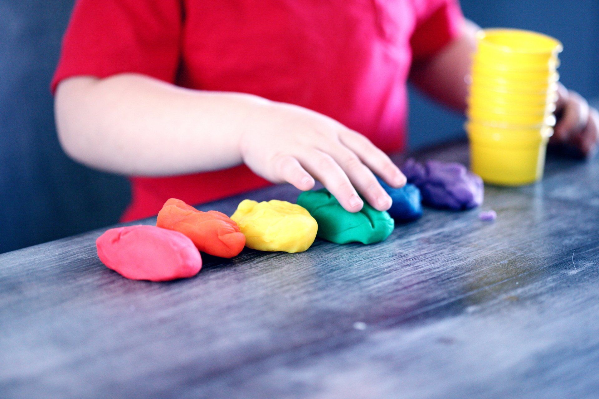 A child is playing with play dough on a table.