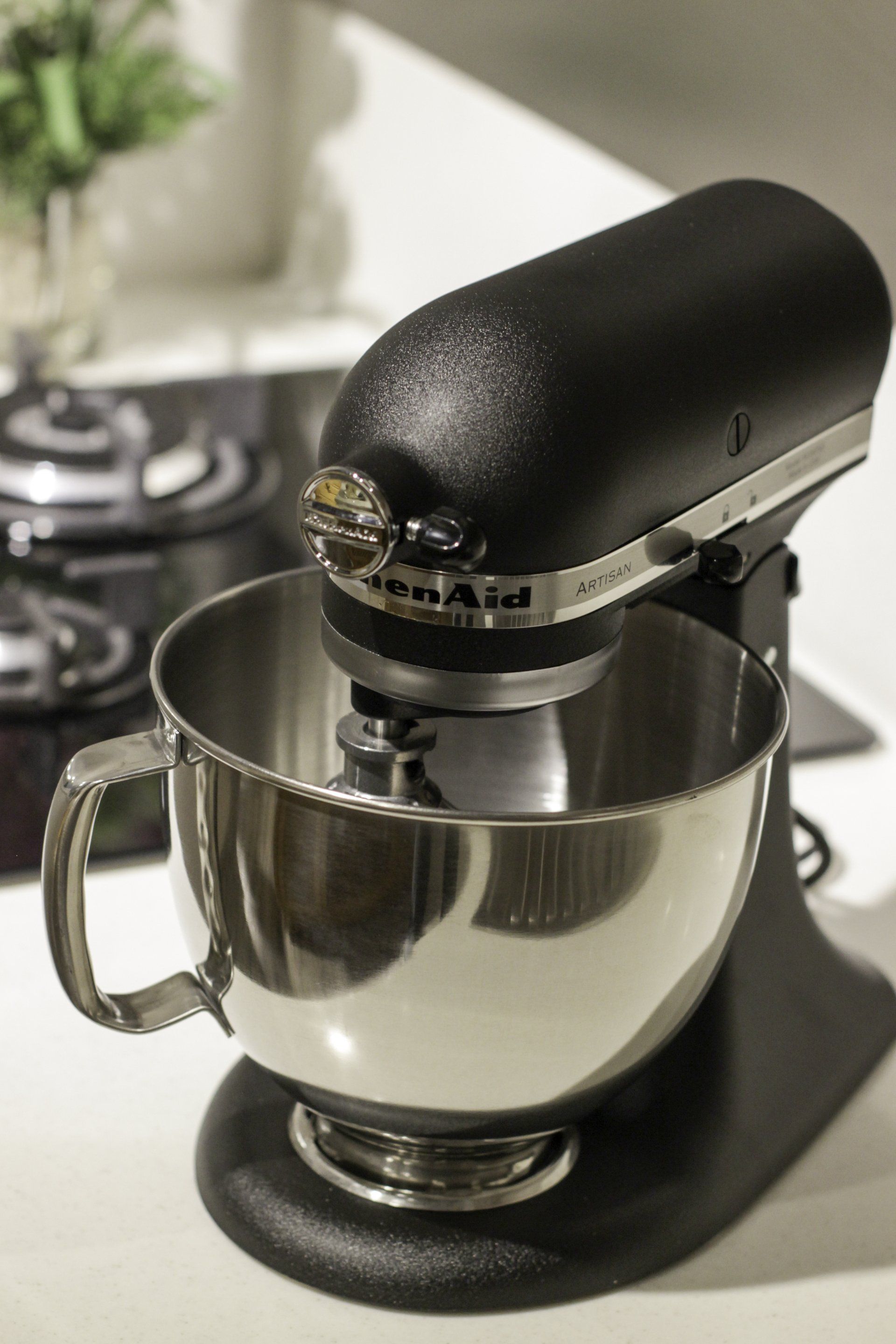 A black kitchenaid mixer is sitting on a counter next to a stove.