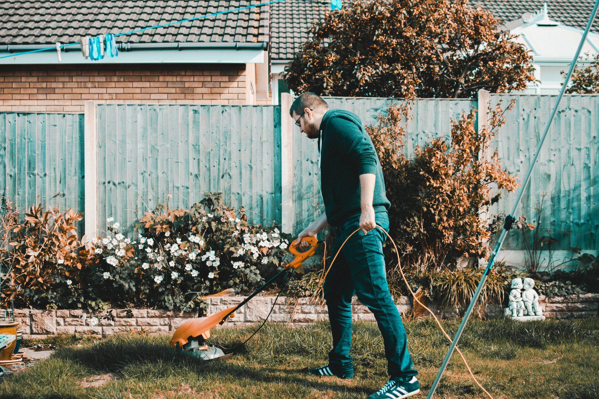 a man is using a lawn mower to cut the grass in his backyard .