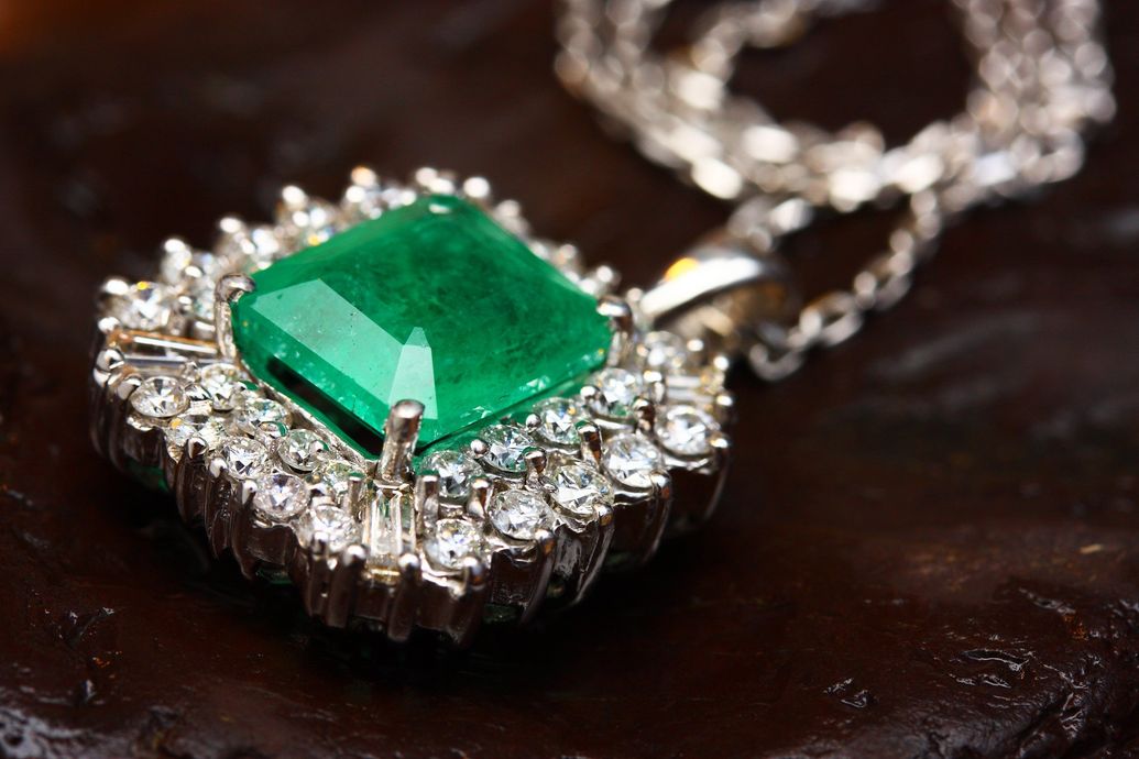 A close up of a necklace with an emerald and diamonds