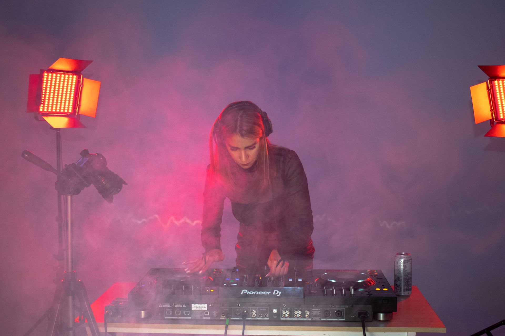 A woman is playing a dj set in a dark room.