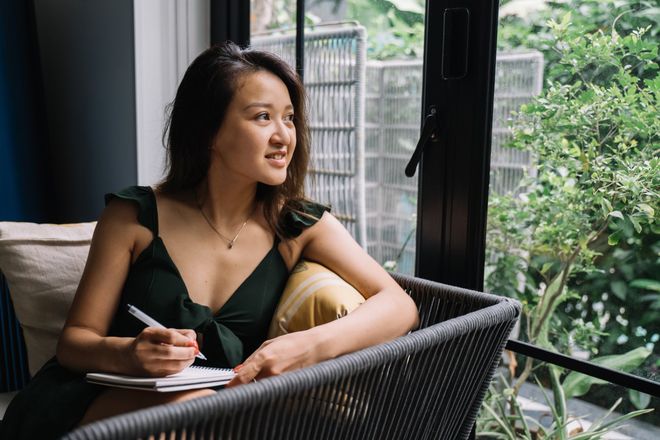 woman journaling and looking out a window