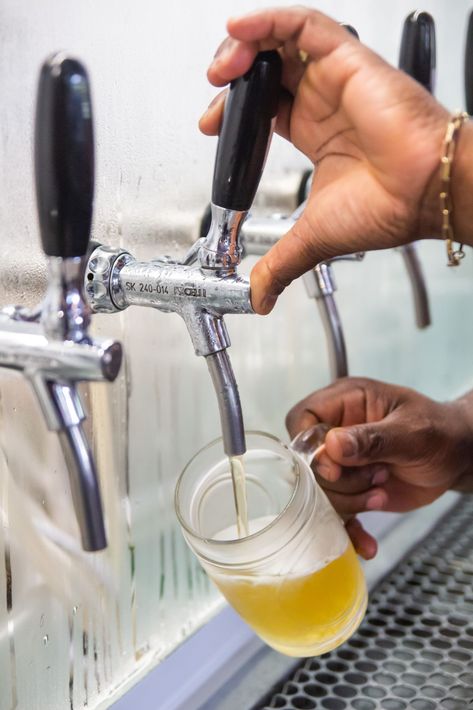 a person is pouring beer into a glass from a tap