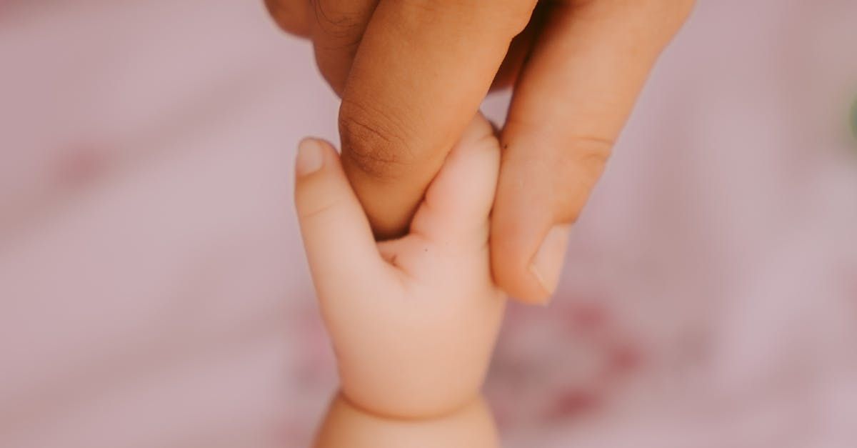 Um close de uma pessoa segurando a mão de um bebê.