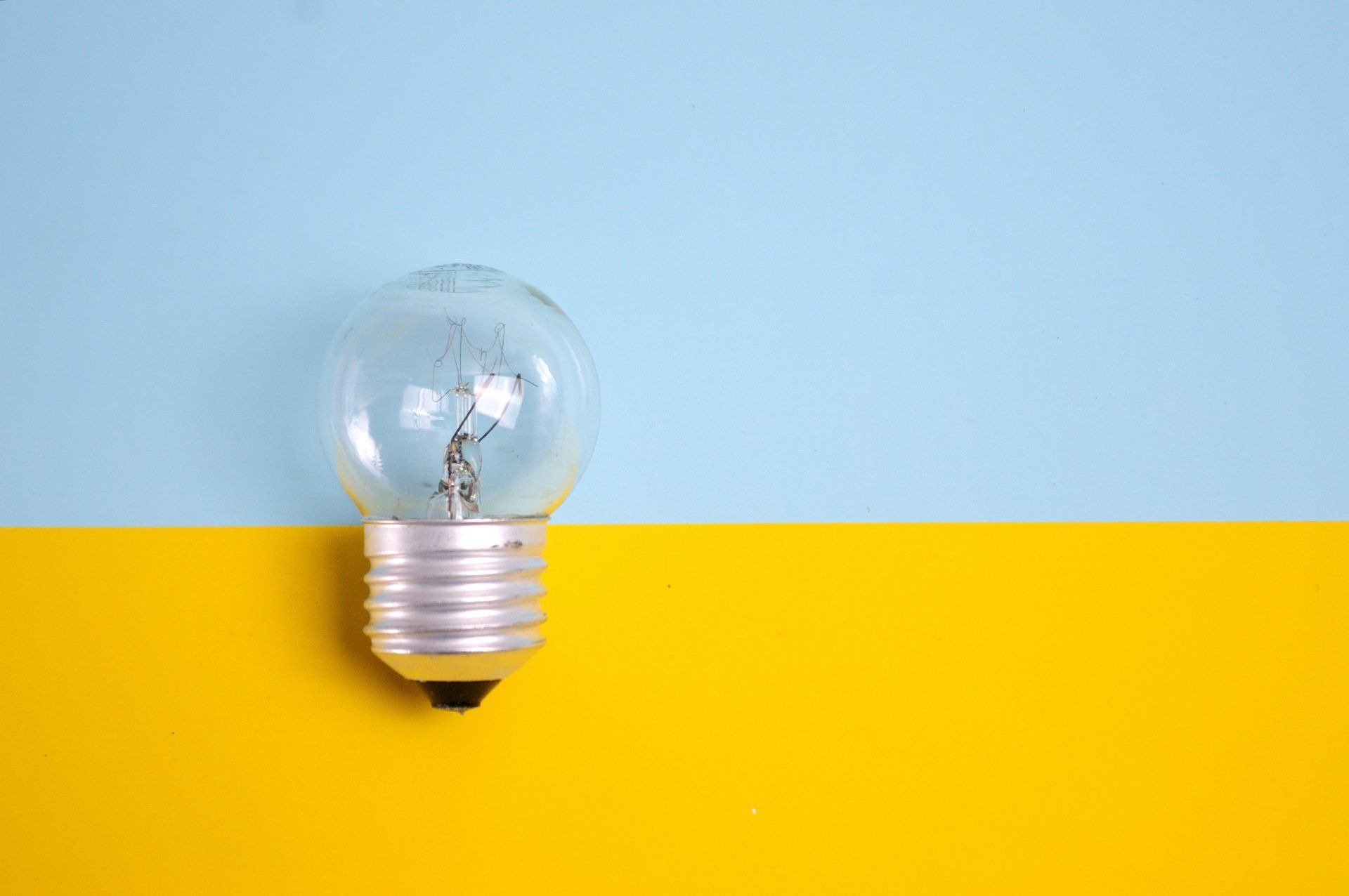 a light bulb is sitting on a yellow and blue background .