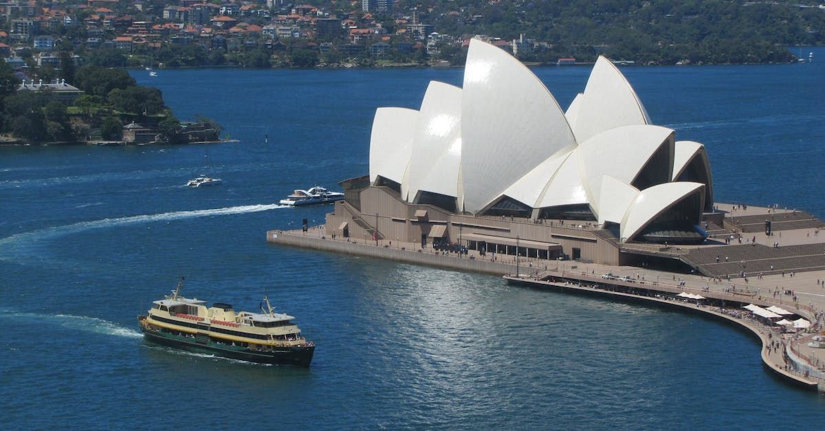 The sydney opera house is lit up at night with a bridge in the background.