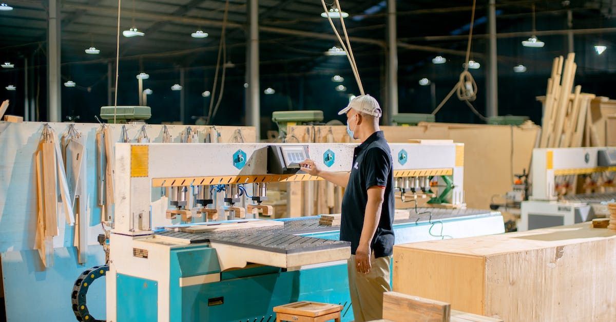 A man is standing in front of a machine in a factory.