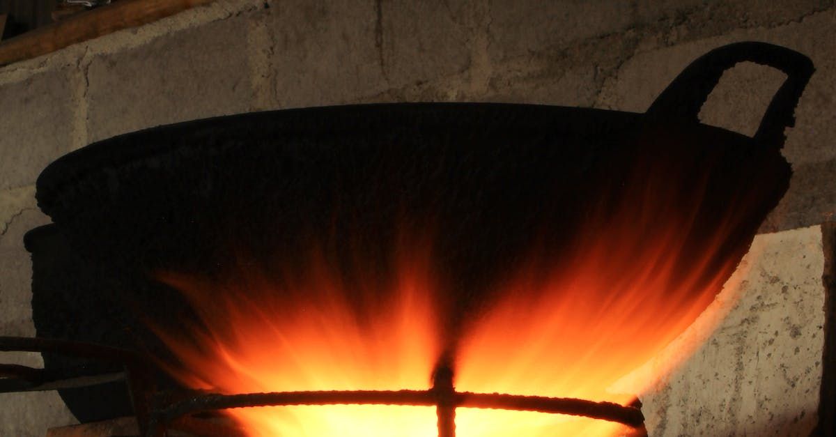 A brick fireplace with a large pot in the center, with fire under it