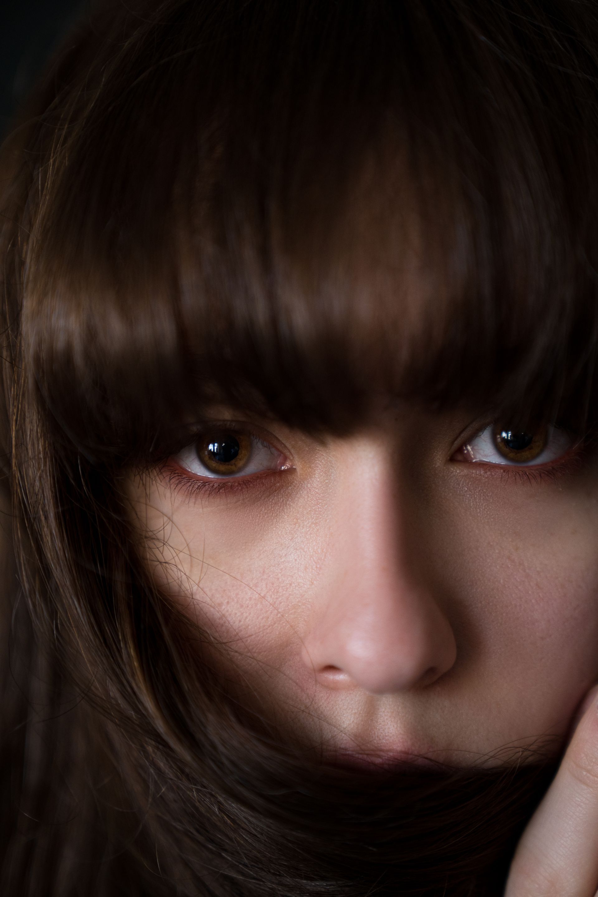 Close-up of a person with brown hair and bangs; eyes looking directly at the viewer.