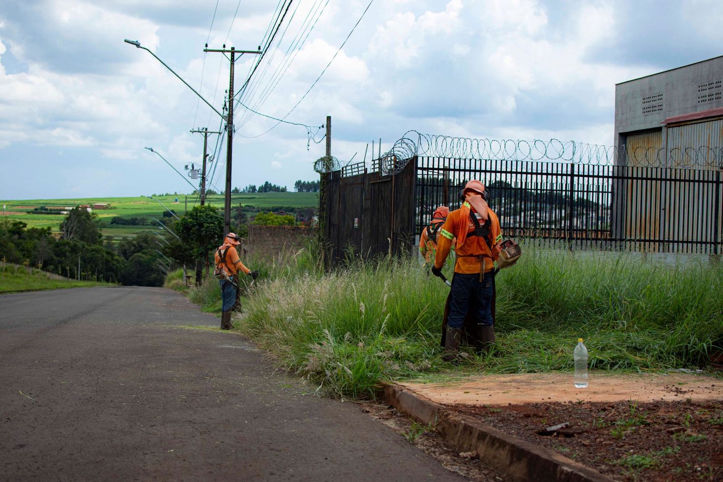 Two men are mowing grass on the side of the road.