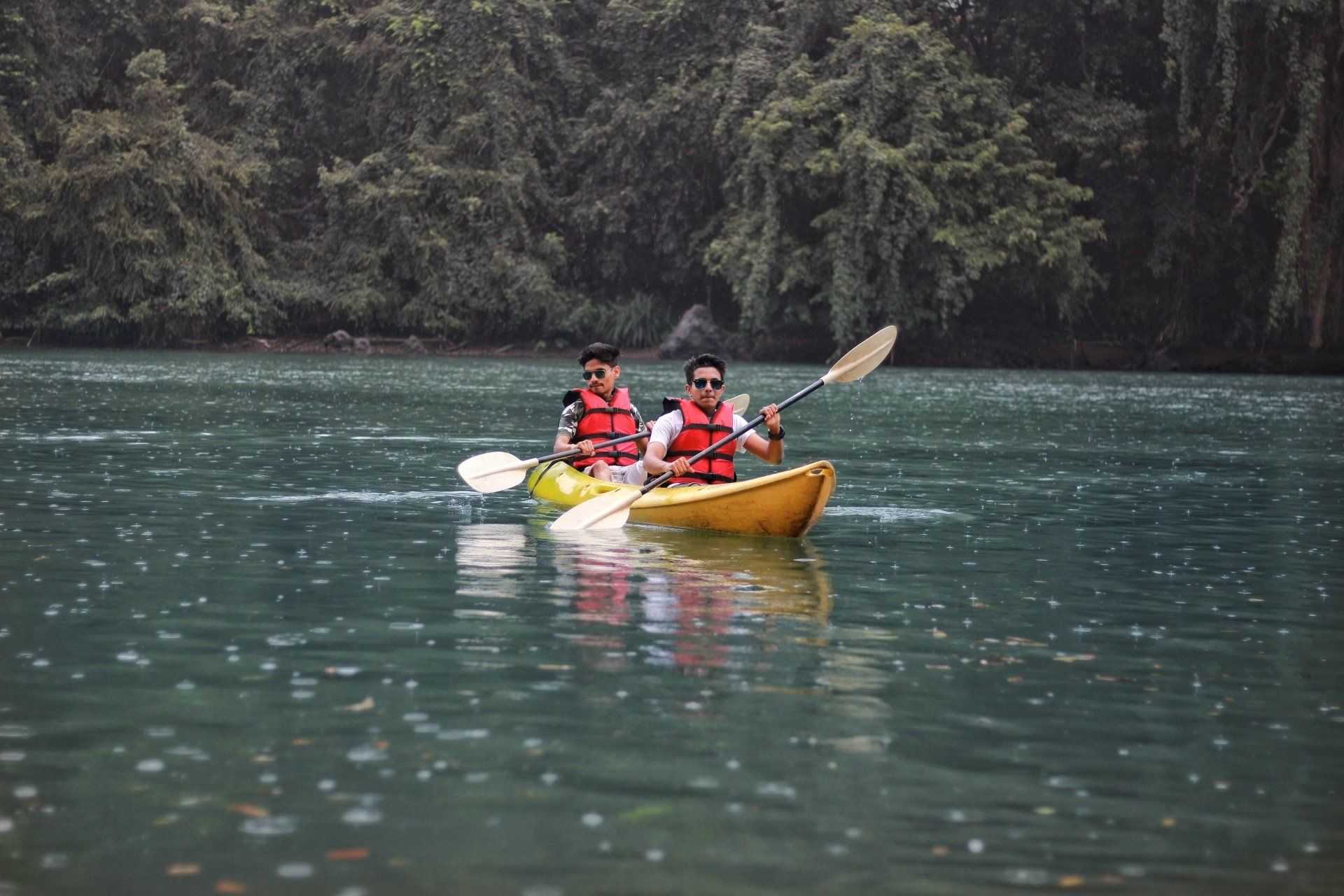 Two people in kayaks on a lake with trees in the background