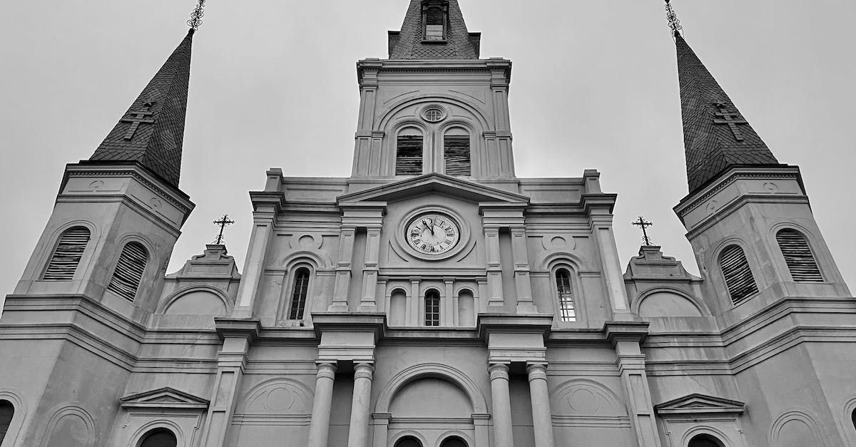 A black and white photo of a large church with a clock on the front.