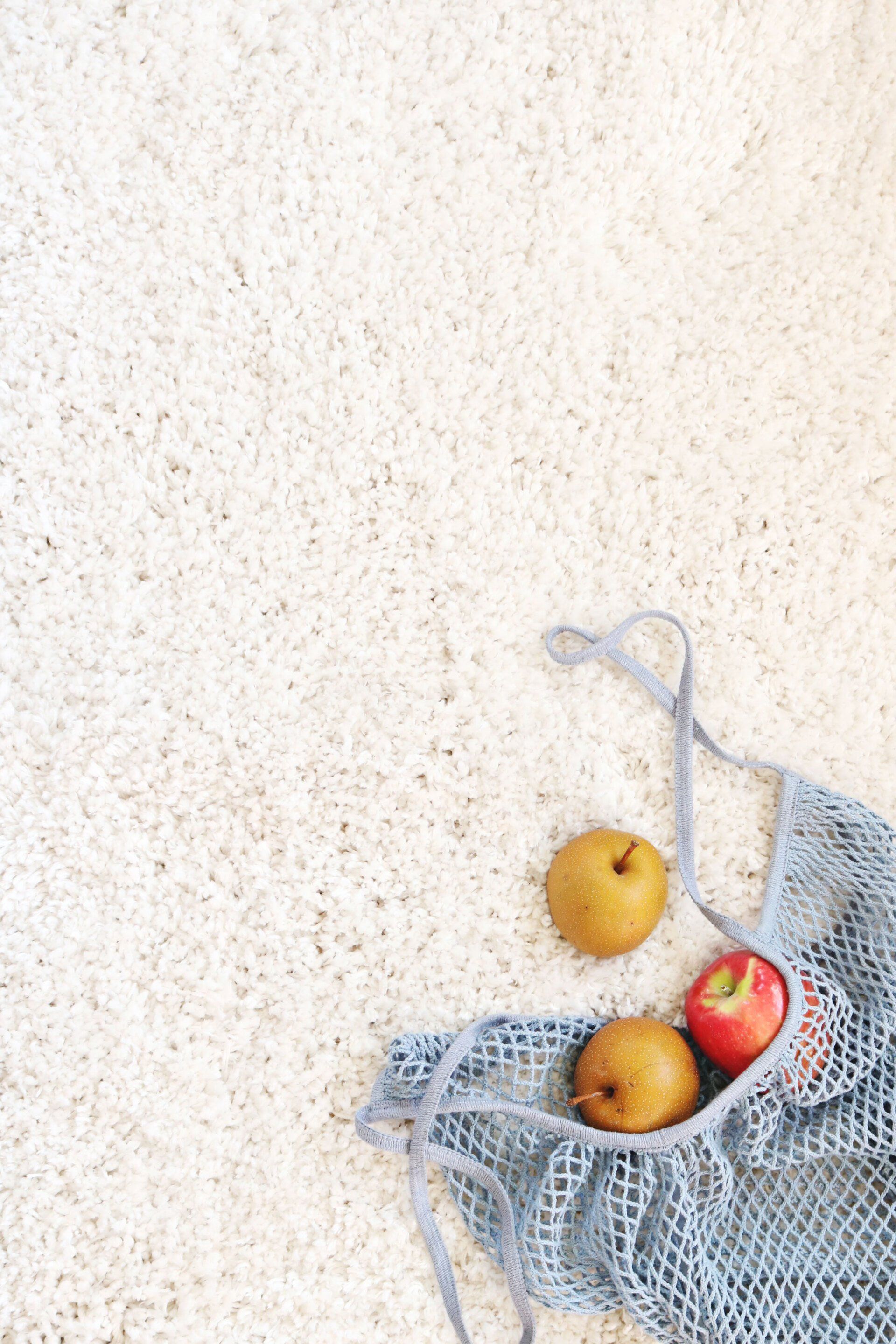 Two apples and two pears are in a mesh bag on the floor.