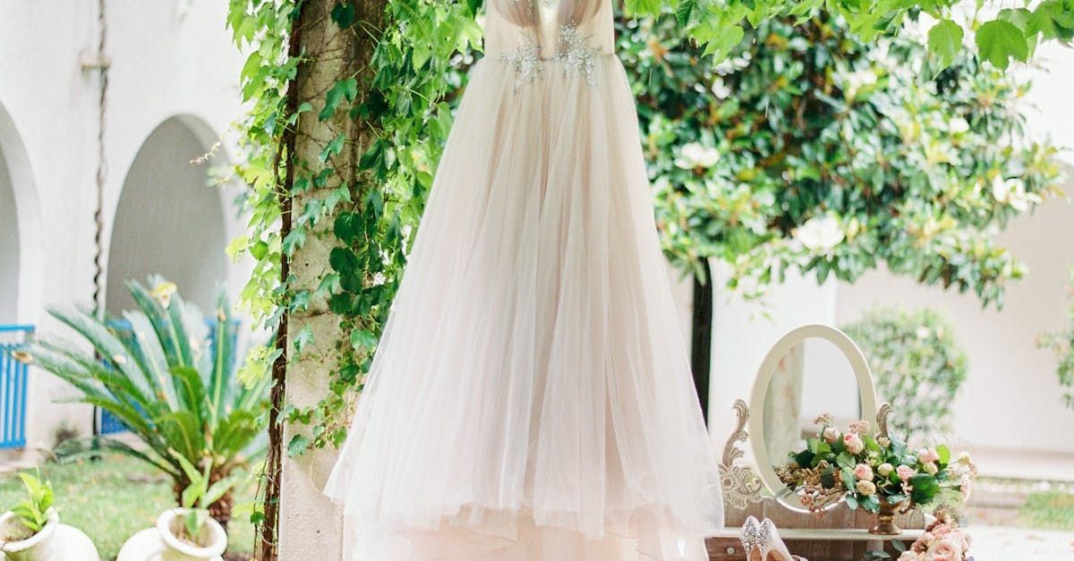 a wedding dress is hanging from a tree in a garden.