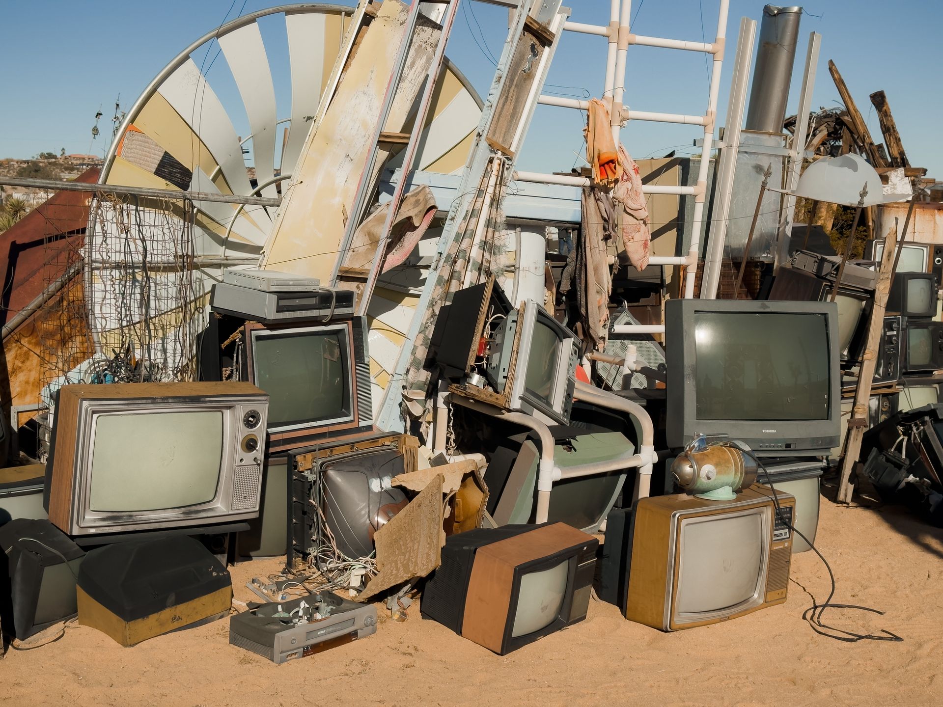 A pile of old televisions and a windmill in the background