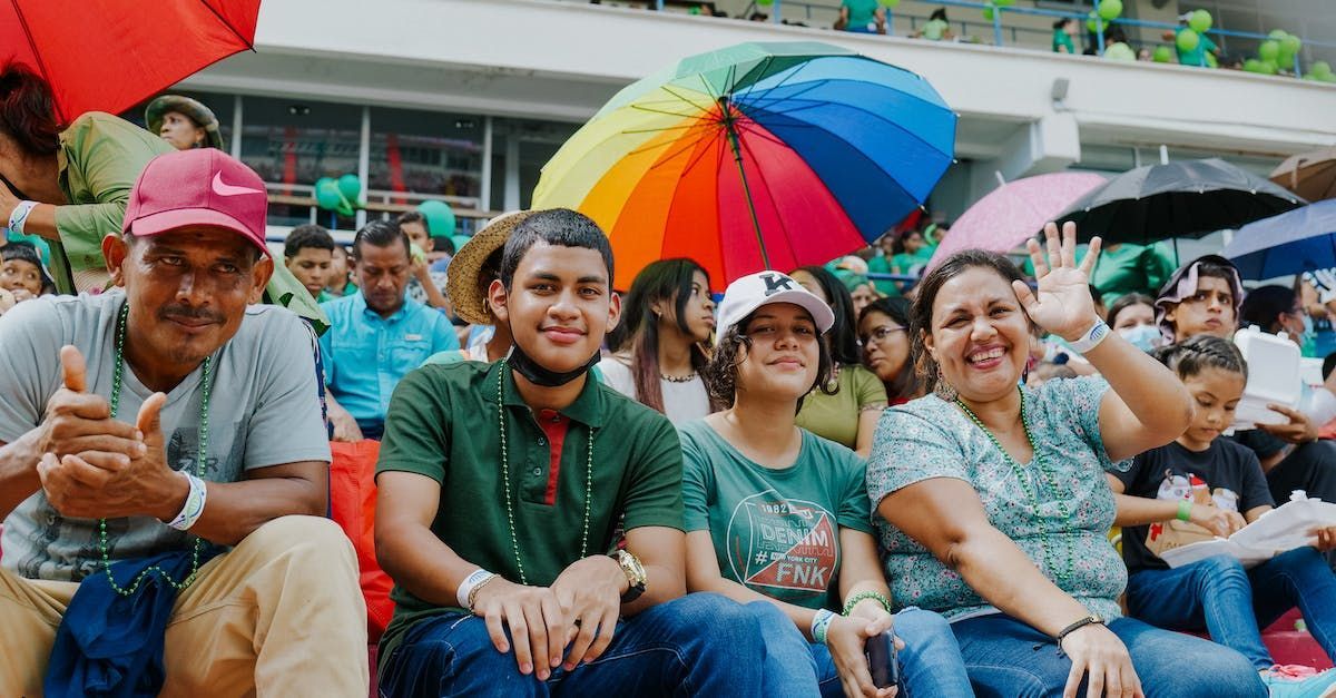 a group of people are sitting under umbrellas in a crowd .