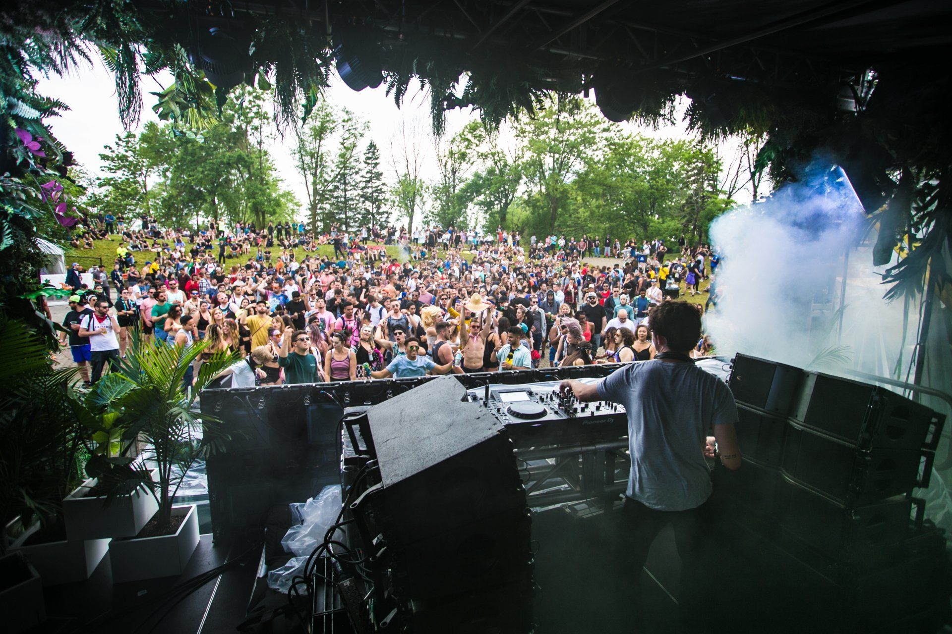 A dj is playing music in front of a crowd at a festival.