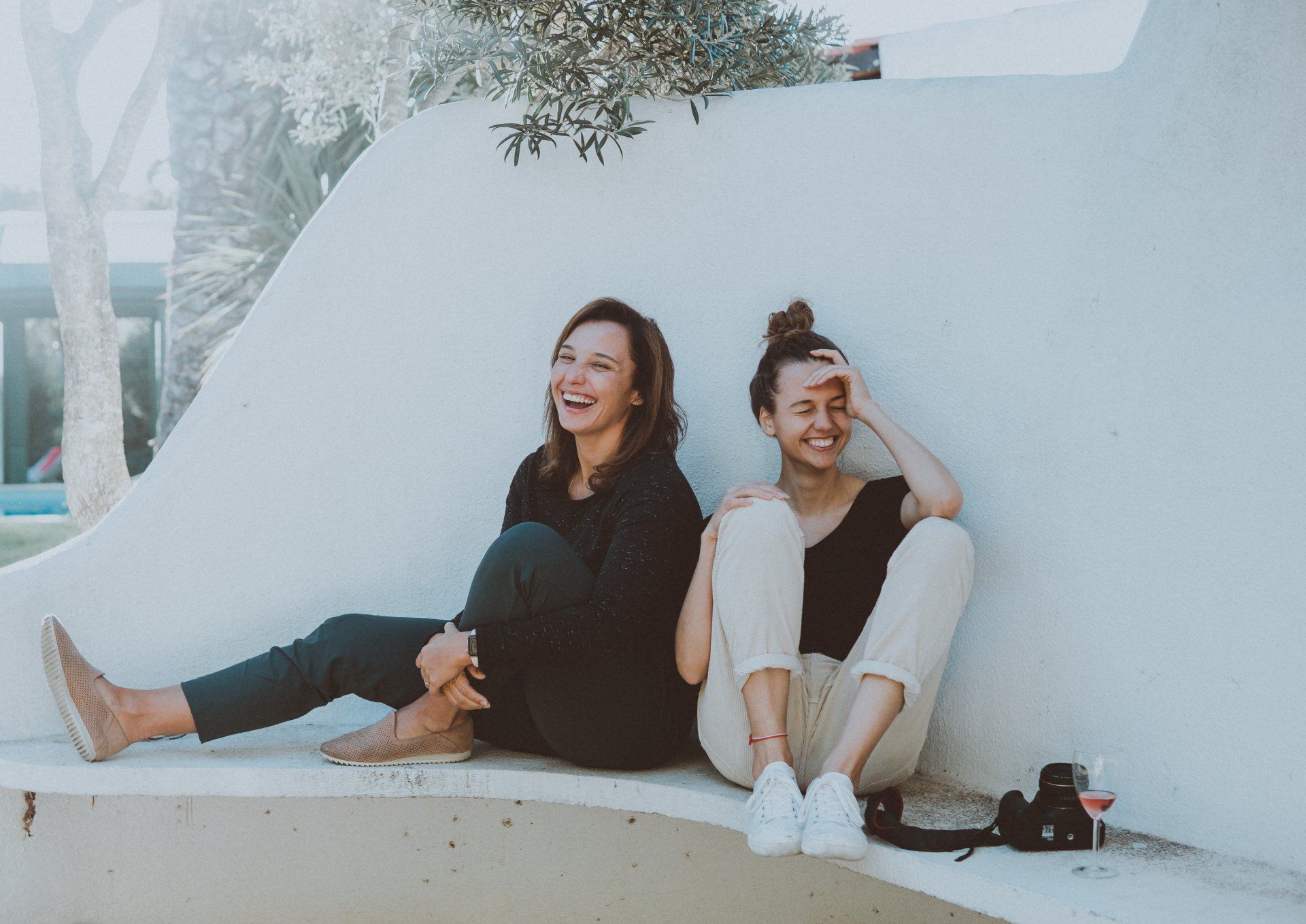 due donne sono sedute una accanto all'altra su una panchina e ridono.