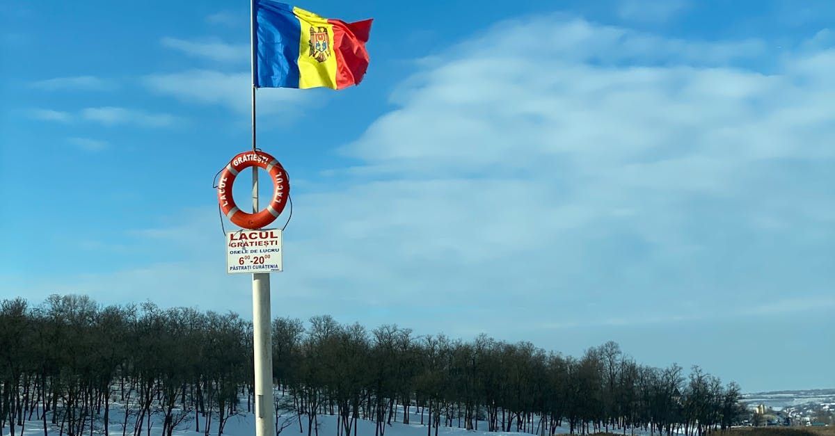 Moldovas flag vajer over en stang med en redningsvest og et skilt mod en blå himmel.