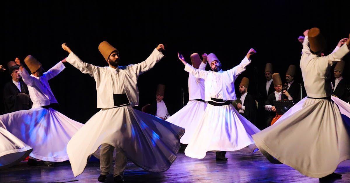 A group of men in white dresses and hats are dancing on a stage.