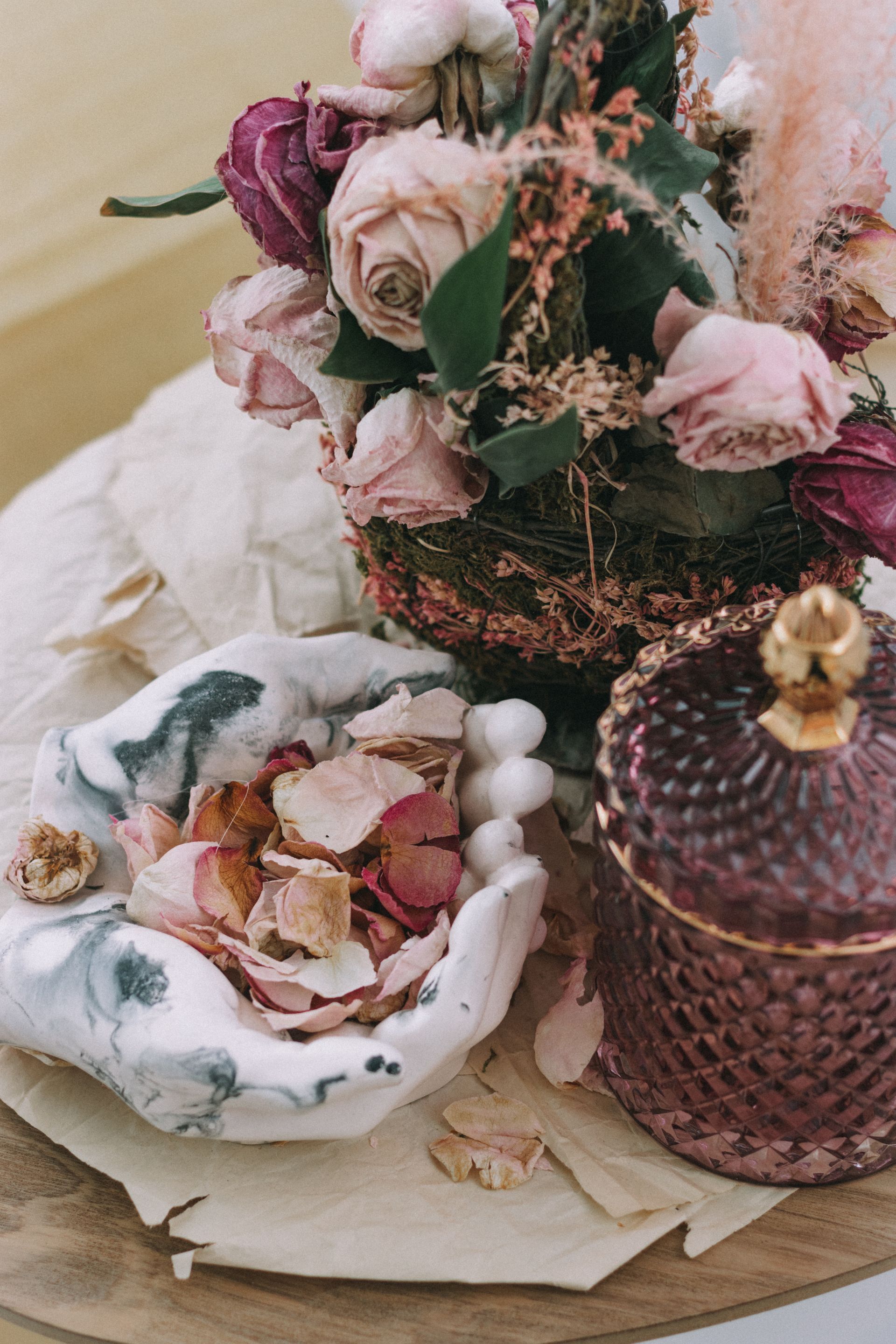 Potpourri sits in a hands-shaped bowl near a dried flower bouquet