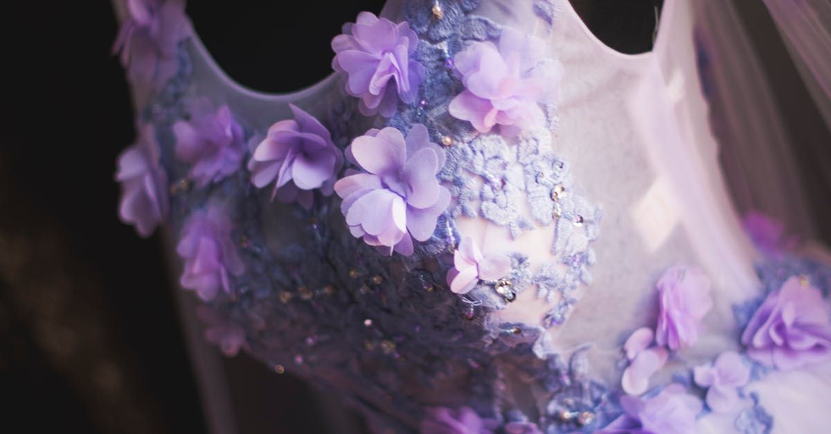 A close up of a white dress with purple flowers on it.