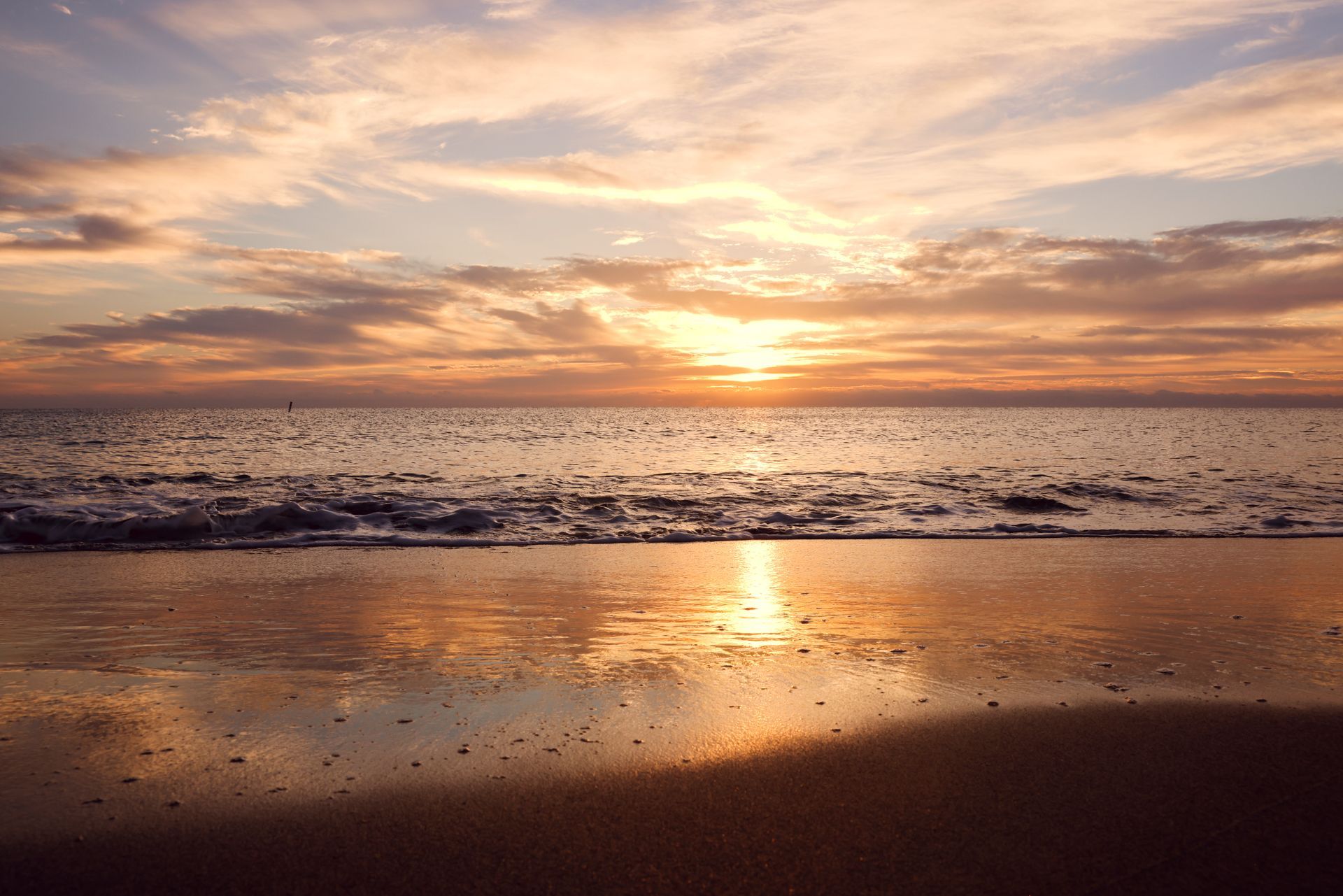 The sun is setting over the ocean and the waves are crashing on the beach