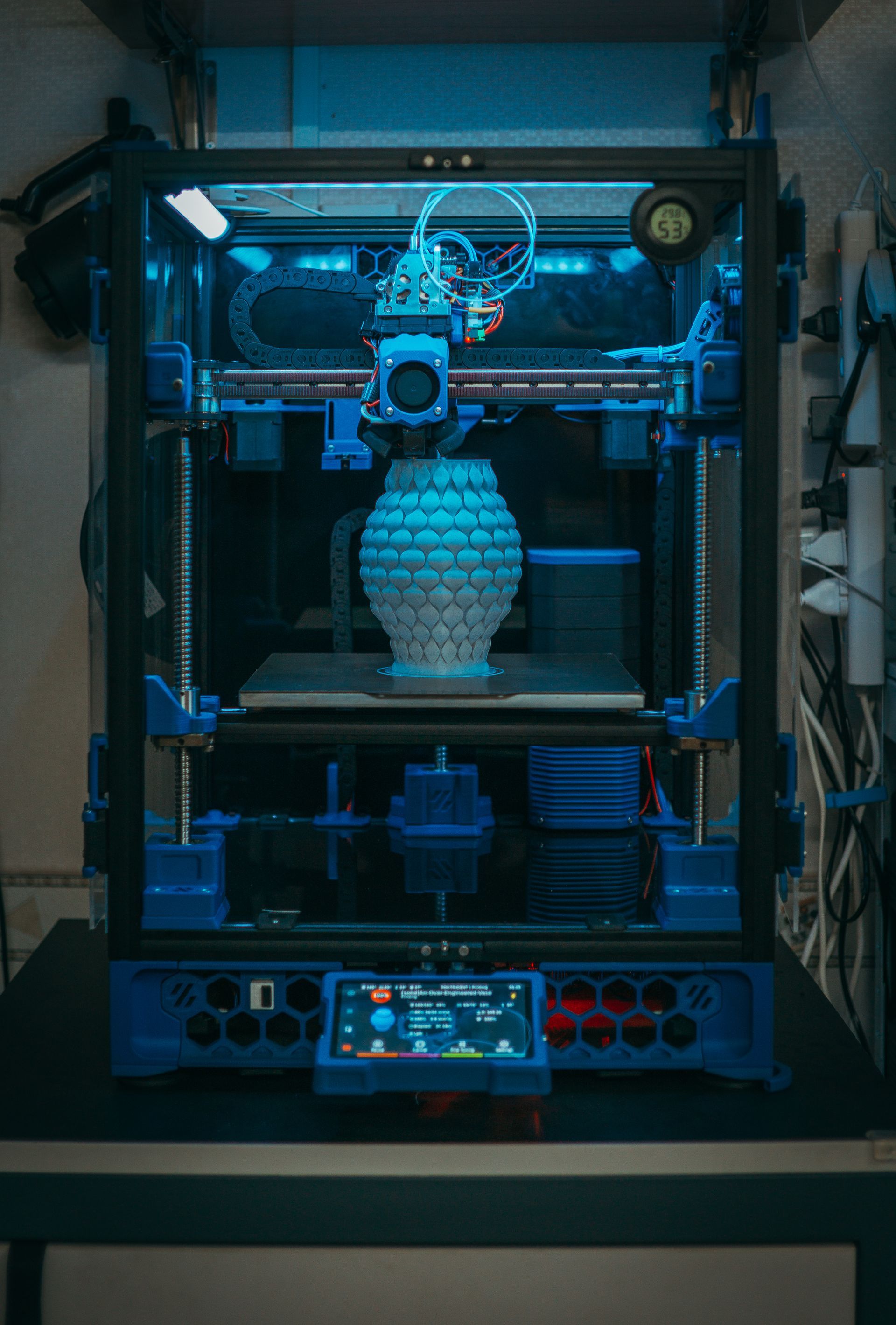 Uma impressora 3D está imprimindo um vaso em uma mesa.