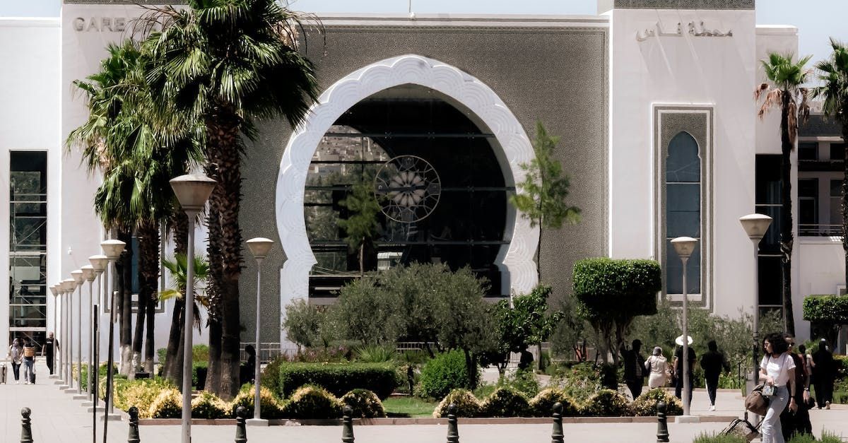 A building with arabic writing on it is surrounded by palm trees