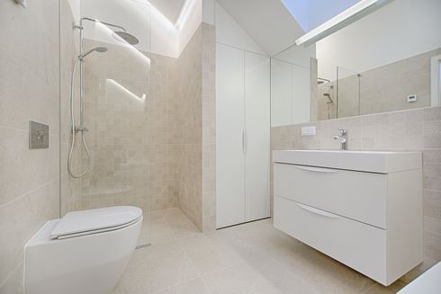 A bathroom with a toilet , sink , shower and mirror.