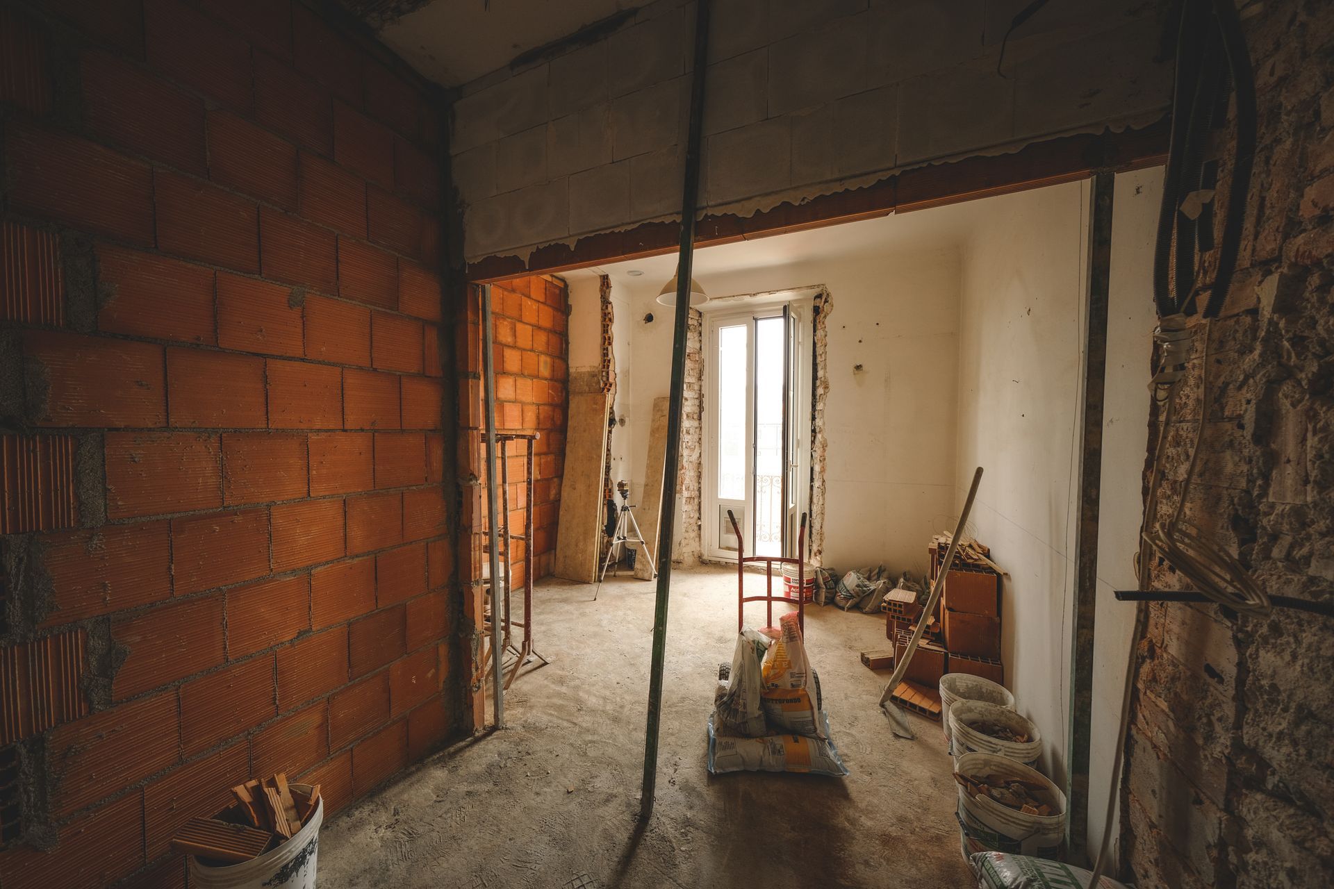 A room under construction with a brick wall and a window.