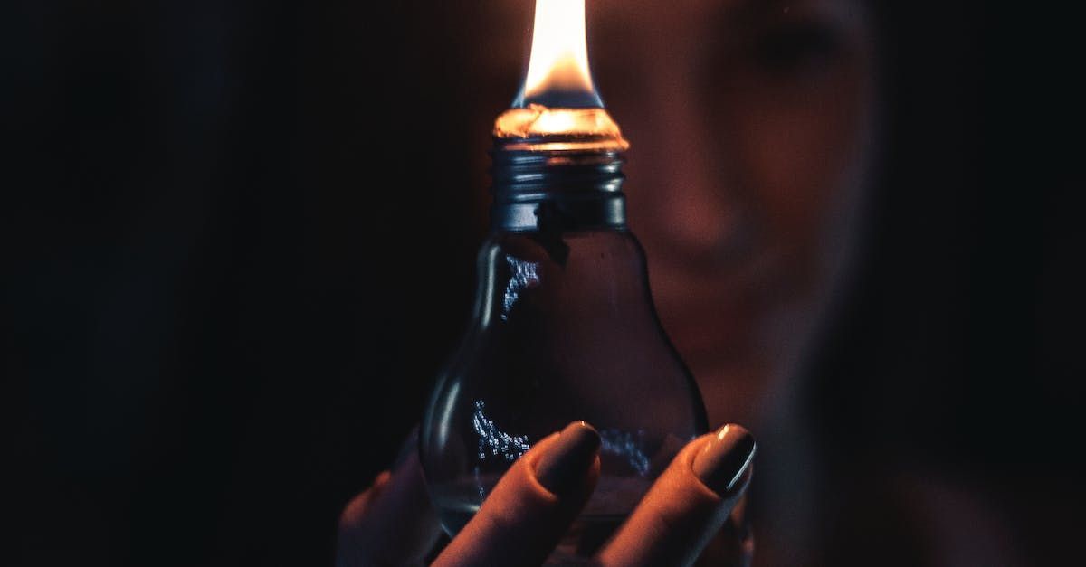 low light image of a woman holding a light bulb with a flame coming out of it