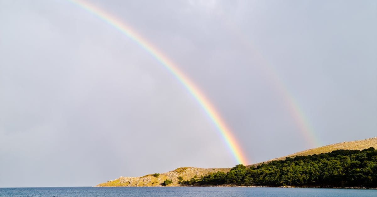 There is a double rainbow in the sky over the ocean.