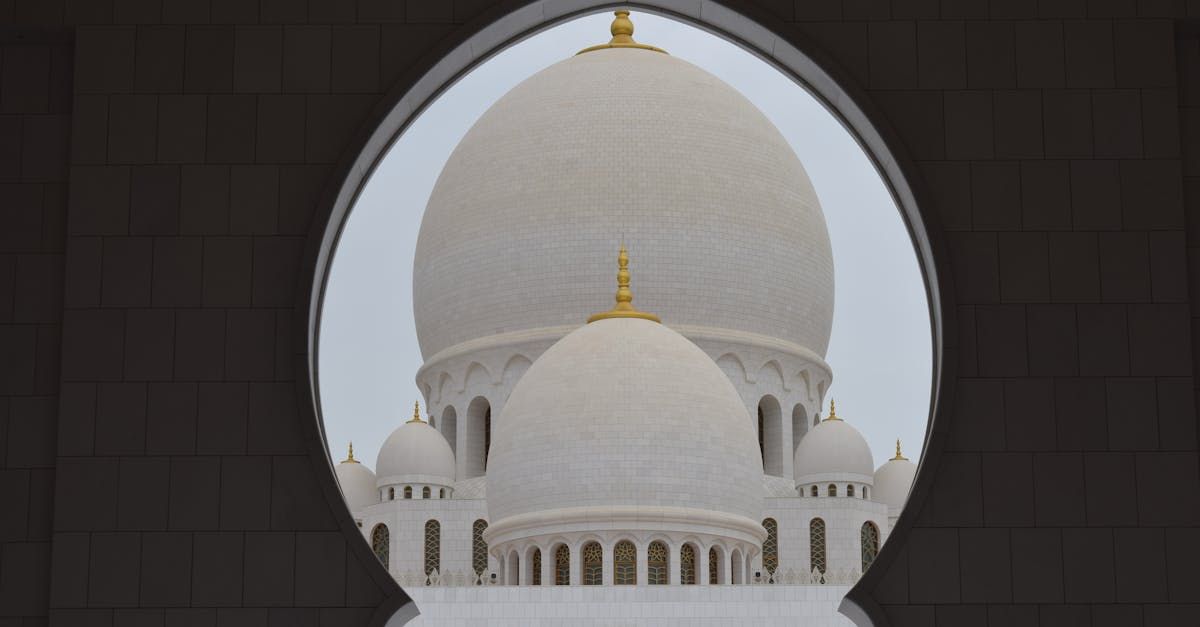 A view of a mosque through a window with a dome in the background.