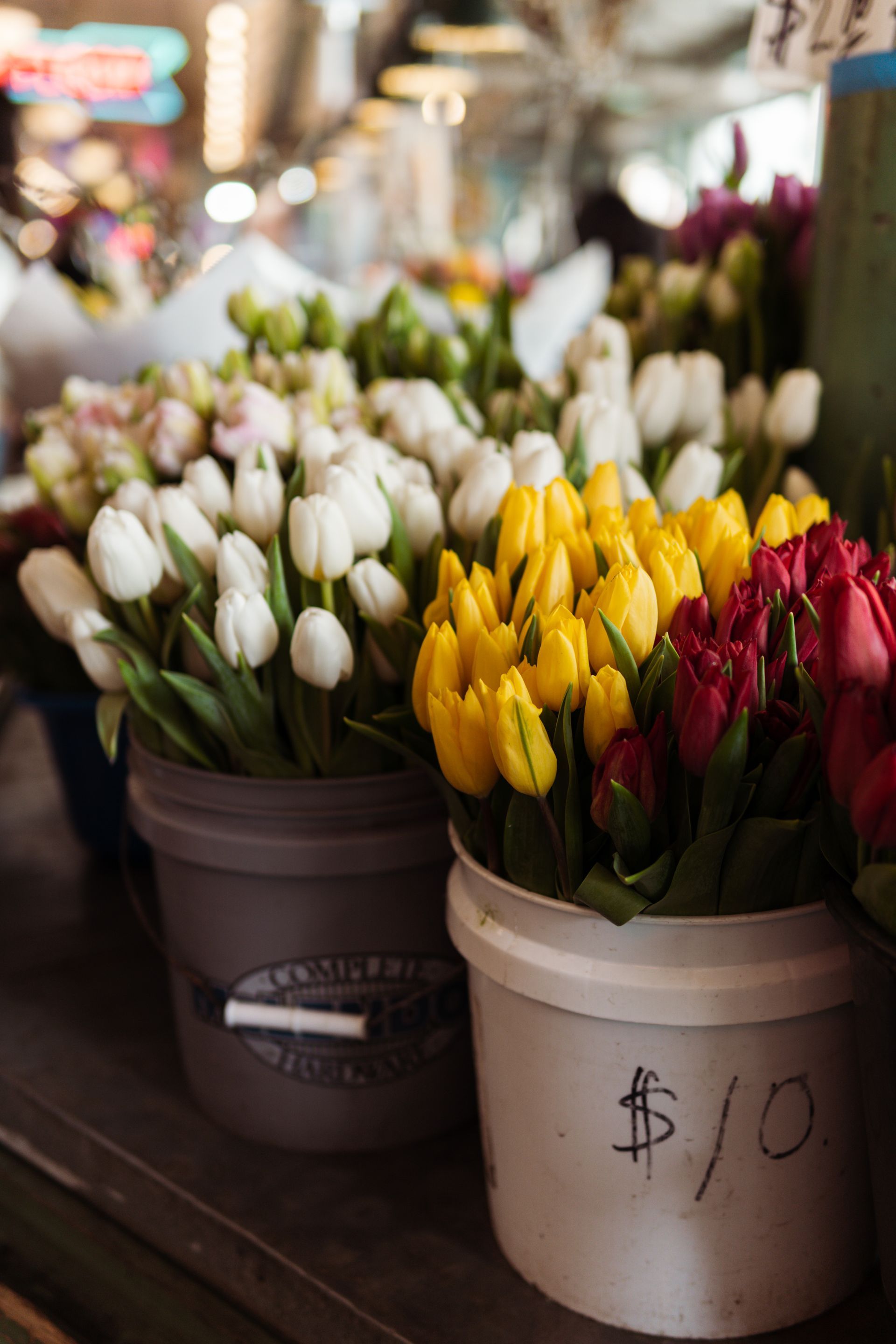 A bunch of buckets filled with flowers are sitting on a table.