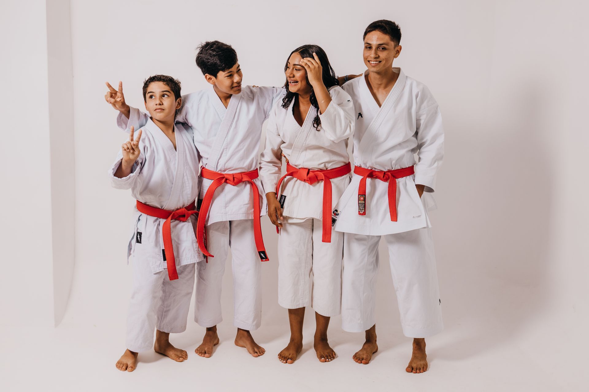 A group of people wearing karate uniforms with red belts are standing next to each other.