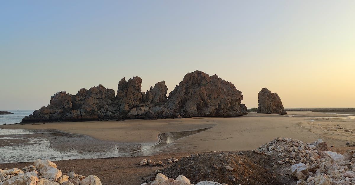 A large rock formation on a beach next to the ocean.
