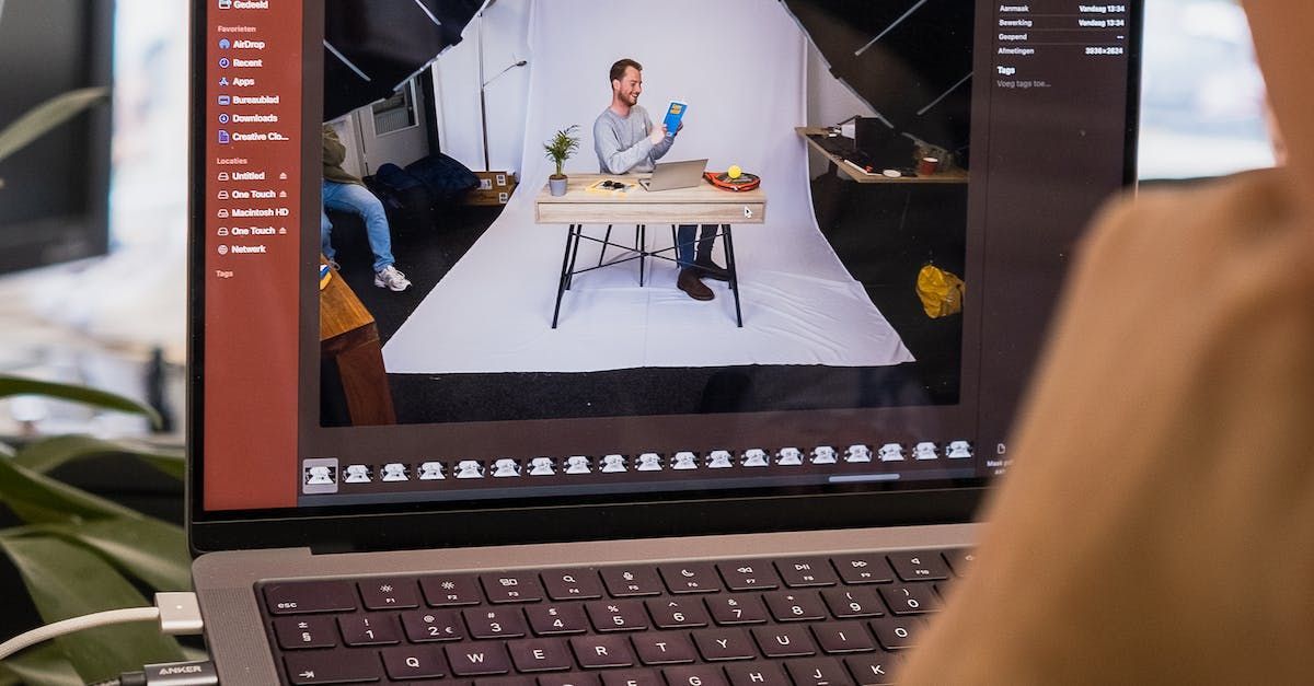 a person is using a laptop computer to take a picture of a man sitting at a table .