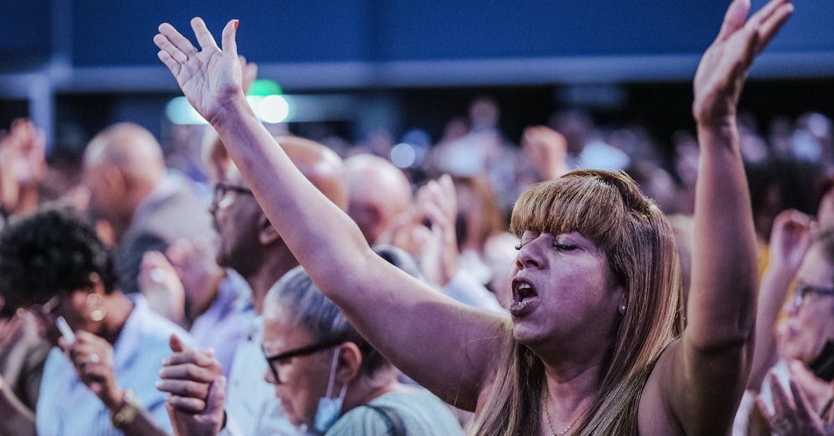 A woman is standing in a crowd with her arms in the air.